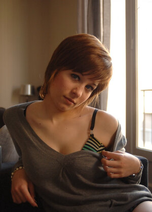 Playful short-haired lassie pulls off sweater to erotically pose in undies