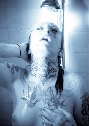 Woman with a tattooed body takes a shower and brandishes her private segments