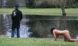 Master walks with dominated naked brunette on a leash and additionally ties her up to the tree