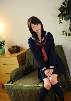 Slender Eastern dame in college uniform smiles so charming and watches into camera