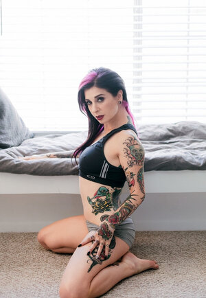 Tattooed female poses in bedroom in underwear that accentuates her assets