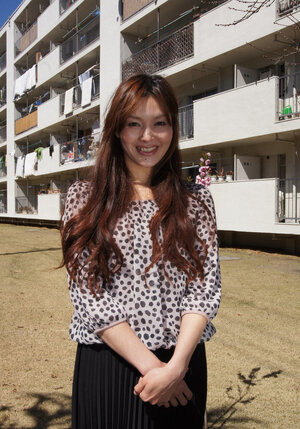 Eastern redhead in a shirt poses for photographer against a apartment building