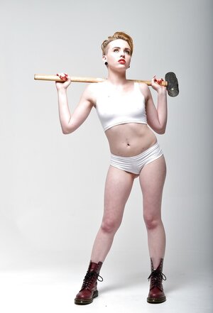 Pale-skinned whore with short red hair and tongue piercing holds sledgehammer
