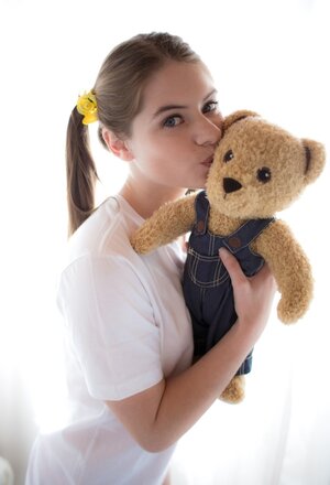 Innocent teenage enters the room with Teddy in hands and puts it aside to strip