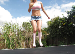 Cheerful young and fresh woman jumps on a trampoline and exposes her big tits