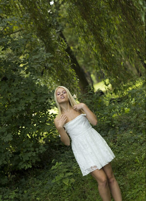 Joyful blonde takes off white dress & underwear during walk in the park